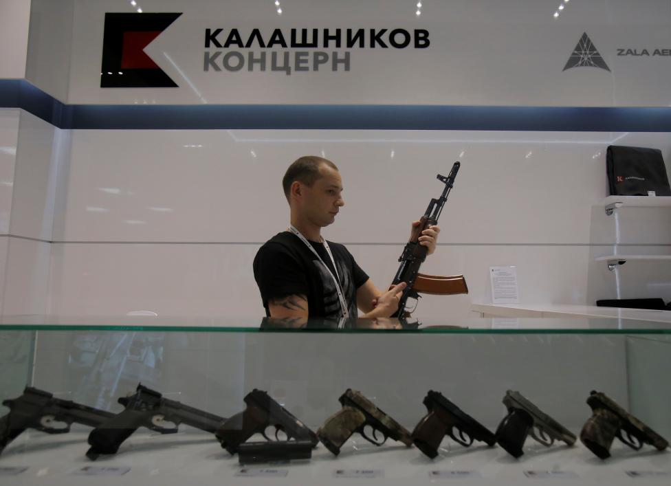 A salesperson shows a model AK-47 assault rifle to customers at the newly opened Gunmaker Kalashnikov souvenir store in Moscow's Sheremetyevo airport