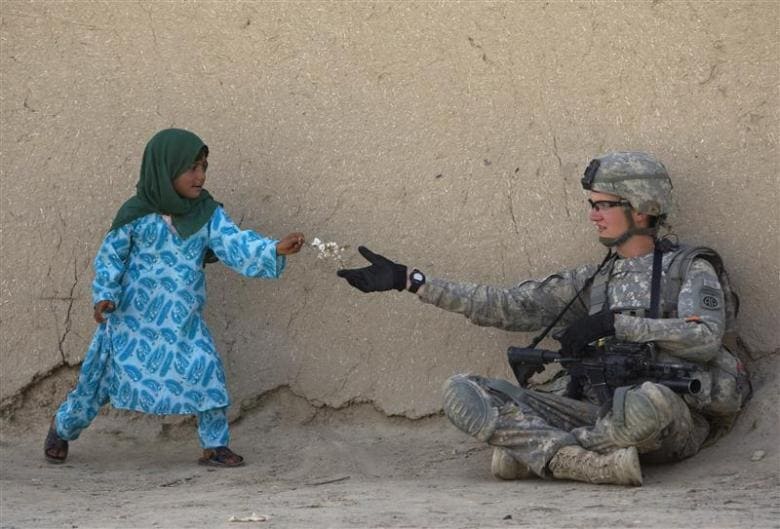 U.S. Army Private First Class Danny Comley of Camdenton Missouri, assigned to Delta Company 4th Brigade combat team,2-508, 82nd parachute infantry Regiment, receives flowers from an Afghan girl during a patrol in the Arghandab valley in Kandahar province, southern Afghanistan February 24, 2010. REUTERS/Baz Ratner (AFGHANISTAN - Tags: CIVIL UNREST CONFLICT IMAGES OF THE DAY)