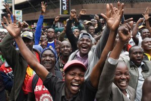 Kenyans watch a big screen on October 12, 2019, in Nairobi as they celebrate Kenya's Eliud Kipchoge victory. - Kenya's Eliud Kipchoge, on October 12, 2019, made history, busting the mythical two-hour barrier for the marathon on a specially prepared course in a huge Vienna park. With an unofficial time of 1hr 59min 40.2sec, the Olympic champion became the first ever to run a marathon in under two hours in the Prater park with the course readied to make it as even as possible. (Photo by SIMON MAINA / AFP) (Photo by SIMON MAINA/AFP via Getty Images)