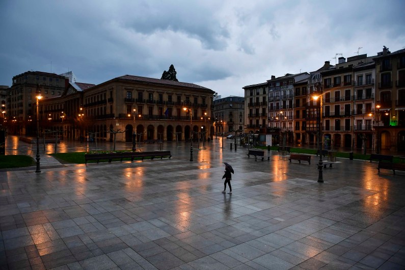 A person walks through an empty Plaza del Castillo square in the old city, in Pamplona, northern Spain, Sunday, March 15, 2020. Spain's prime minister announced a two-week state of emergency from Saturday in a bid to contain the new coronavirus outbreak. For most people, the new COVID-19 coronavirus causes only mild or moderate symptoms, such as fever and cough, but for some, especially older adults and people with existing health problems, it can cause more severe illness, including pneumonia. (AP Photo/Alvaro Barrientos)